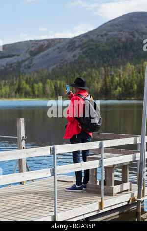 Finnland, Lappland, Mann mit Handy Bild am See Stockfoto