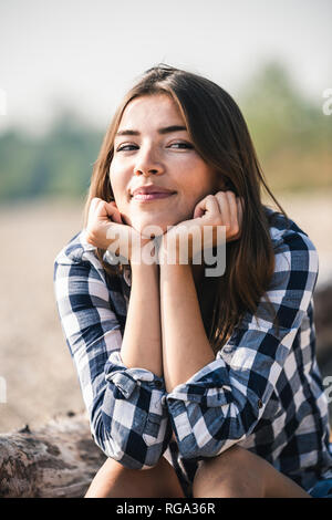 Portrait von lächelnden jungen Frau sitzt im Freien Stockfoto