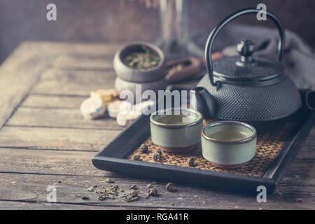 Still-Leben der japanischen gesunden grünen Tee in einem kleinen Tassen und Teekanne über dunklen Hintergrund Stockfoto