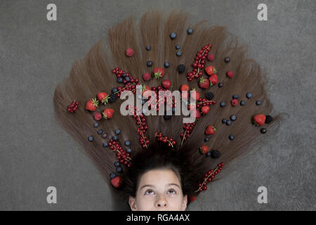 Portrait von Mädchen liegt auf dem Boden mit Früchten auf Haar suchen Stockfoto