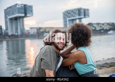 Deutschland, Köln, glückliches Paar entspannende im Riverside bei Sonnenuntergang Stockfoto