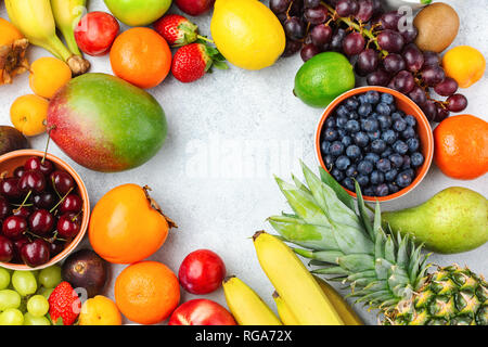 Rainbow Früchte Hintergrund Rahmen, Pflaumen Erdbeeren Himbeeren Orangen, Äpfel, Kiwis, Weintrauben, Heidelbeeren mango Kaki auf weißem Tabelle, Ansicht von oben, kopieren Stockfoto