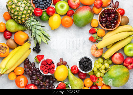 Rainbow Früchte Hintergrund Rahmen, Pflaumen Erdbeeren Himbeeren Orangen, Äpfel, Kiwis, Weintrauben, Heidelbeeren mango Kaki auf weißem Tabelle, Ansicht von oben, kopieren Stockfoto