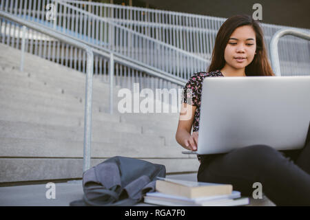 Junge asiatische Studentin mit einem Laptop auf dem Campus Stockfoto