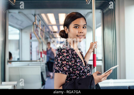Lächelnd asiatische Studenten pendeln auf einer Zugfahrt zur Arbeit Stockfoto