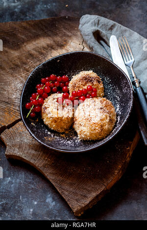 Pflaume gefüllte süße Knödel mit Kokosnuss - Zimt Kruste und rote Johannisbeeren Stockfoto