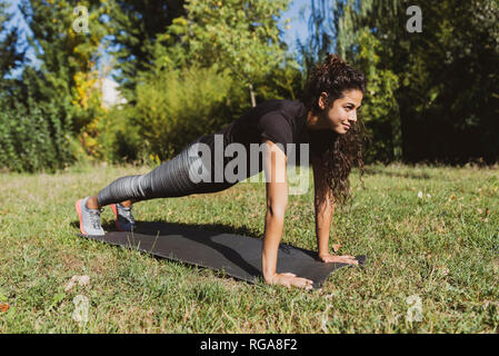 Sportliche junge Frau, Push-ups auf einer Wiese Stockfoto