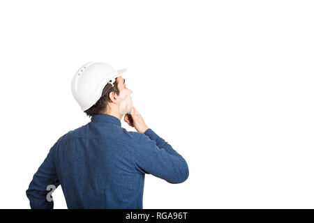 Ansicht der Rückseite des jungen Mann Ingenieur das Tragen schützender helm die Hand unter dem Kinn nachdenklich über weißen Hintergrund mit Kopie spa Suchen isoliert Stockfoto