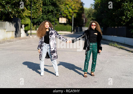 Portrait von modischen Zwillingsschwestern Hände halten Stockfoto