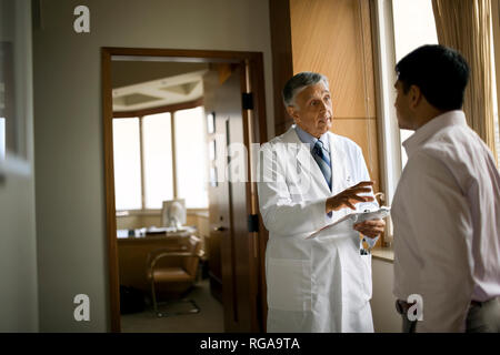 Freundlich leitender Arzt Beratung mit einem Patienten vor seinem Büro. Stockfoto