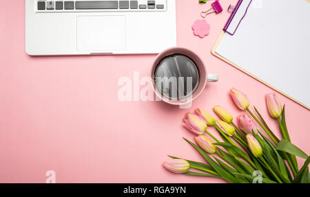 Frauen, Mütter Tag Konzept. Rosa Tulpen Bouquet und Computer Laptop auf Rosa pastell Hintergrund, Ansicht von oben, kopieren Raum Stockfoto