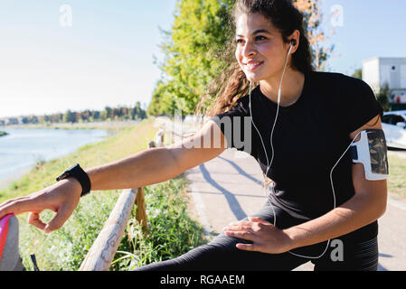 Sportliche junge Frau ihr Bein strecken am Flußufer Stockfoto