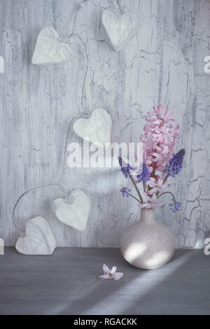 Valentines Tag oder Frühling Feier, Vase mit Hyazinthen Blumen und girlande Lichter in Form von Papier Herzen auf rustikalen Hintergrund Stockfoto