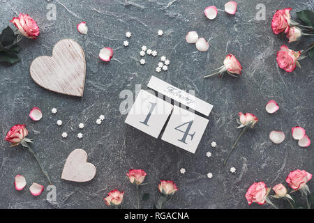 Valentine's Day Feier, flach mit Holz- Kalender, Rosen und Herzen auf dunkelgrauem Hintergrund Stockfoto