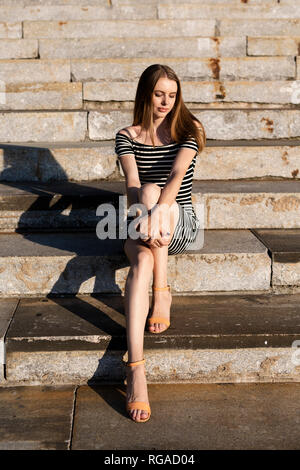 Porträt der jungen Frau sitzt auf der Treppe Sonnenuntergang Stockfoto