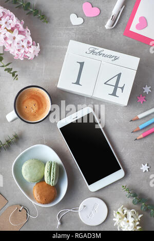 Happy Valentine! Kaffee am Morgen, Holz- Kalender, Macarons, Bleistifte, rosa Hyazinthe Blumen und Eukalyptus auf grauem Stein Tabelle, Ansicht von oben in Flach st Stockfoto