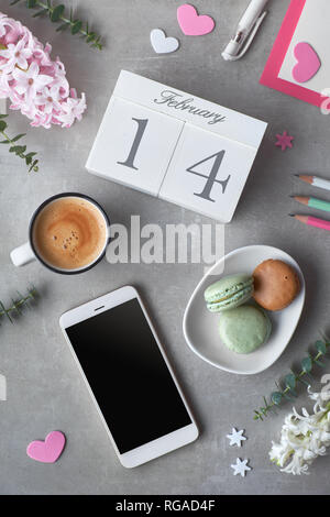 Happy Valentine! Kaffee am Morgen, Holz- Kalender, Macarons, Bleistifte, rosa Hyazinthe Blumen und Eukalyptus auf grauem Stein Tabelle, Ansicht von oben in Flach st Stockfoto