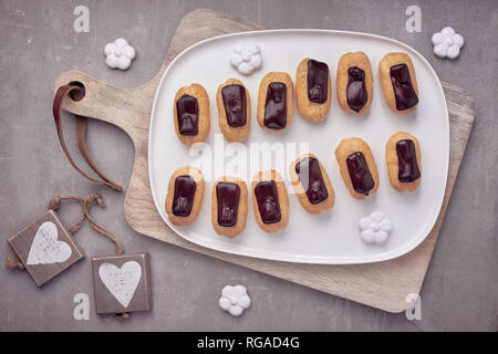 Mini Vanille eclairs mit Schokolade Zuckerguss auf hellen Stein, Ansicht von oben Stockfoto