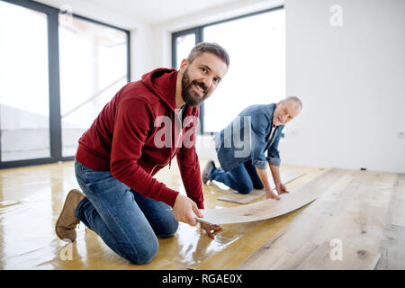 Einen hinteren und Draufsicht reifer Mann mit seinem älteren Vater Festlegung Vinyl Bodenbelag, ein neues Zuhause. Stockfoto