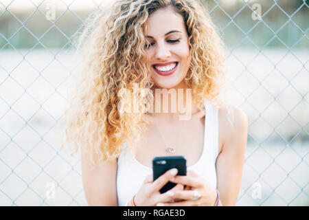 Portrait von Lachen blonde junge Frau am Handy suchen Stockfoto