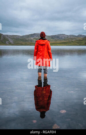 Junger Mann, der Knöchel tief im Wasser, in der Ferne suchen, Ansicht von hinten Stockfoto