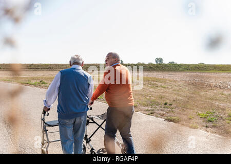 Zwei alte Freunde zu Fuß auf einer Landstraße, mit Rädern, Wanderer Stockfoto