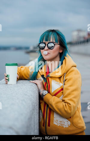 Porträt der jungen Frau mit gefärbtem Haar zu tragen blau verspiegelten Sonnenbrillen und modische Kapuzenjacke Stockfoto