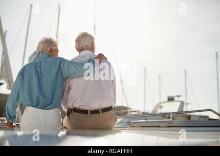 Ältere Frau legt ihre Hand um die Schultern ihres Mannes, wie Sie auf einem Boot mit Blick auf die Marina. Stockfoto