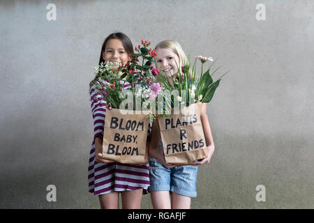 Portrait von zwei lächelnde Mädchen Seite an Seite mit Papiertüten mit Blumen Stockfoto