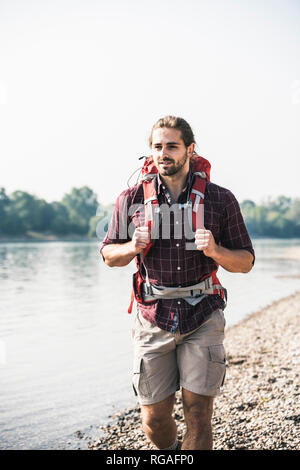 Junger Mann mit Rucksack zu Fuß am Flußufer Stockfoto