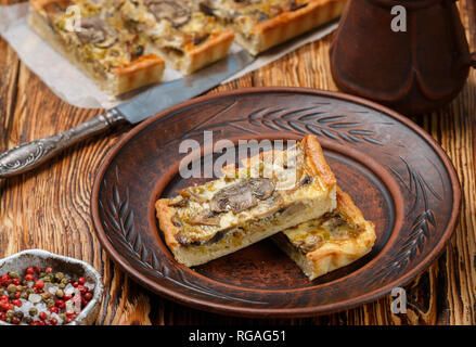 Hausgemachte Törtchen mit Champignons, Lauch, Käse und Thymian auf rustikalen Hintergrund. Traditionelle Snacks Kuchen. Mittag- oder Abendessen für Feinschmecker. Selektiver Fokus Stockfoto