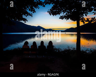 Österreich, Oberösterreich, Salzkammergut, Fuschlsee, Menschen sitzt auf der bank Sonnenuntergang Stockfoto