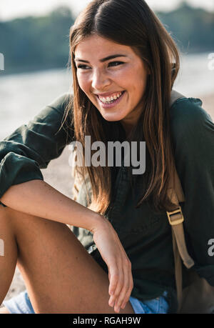 Porträt der glückliche junge Frau sitzt im Freien Stockfoto