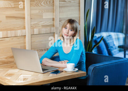 Wissen Sie nicht! Portrait von Traurigkeit müde Junge Mädchen Freelancer mit blonden Bob Haarschnitt Haar in blauen T-Shirt sind allein sitzen im Café und auf der Suche nach einem Stockfoto