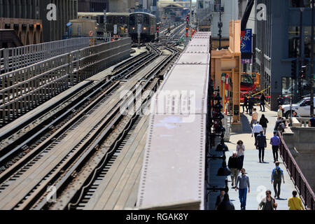 Chicago 'L' Züge auf erhöhten Eisenbahnschienen in der Nähe von Merchandise Mart station mit Fußgängern unter gehen auf die Straße. Illinois/USA Stockfoto