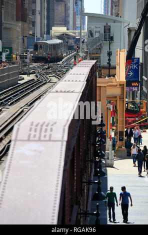 Chicago 'L' Züge auf erhöhten Eisenbahnschienen in der Nähe von Merchandise Mart station mit Fußgängern unter gehen auf die Straße. Illinois/USA Stockfoto