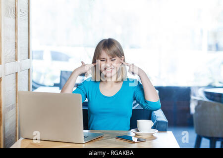 Möchten nicht hören! Portrait von attraktiven interessante junge Mädchen Freelancer in blaue Bluse Sitzen im Cafe und Videokonferenz auf Laptop, coveri Stockfoto