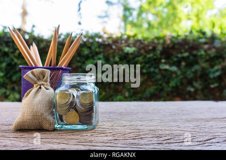 Geld sparen, Investition, Geld, das für die zukünftige, finanzielle Wealth Management Konzept. Münzen in Glas und Bleistift. Bargeld in Hanf Taschen oder Sackleinen sa Stockfoto