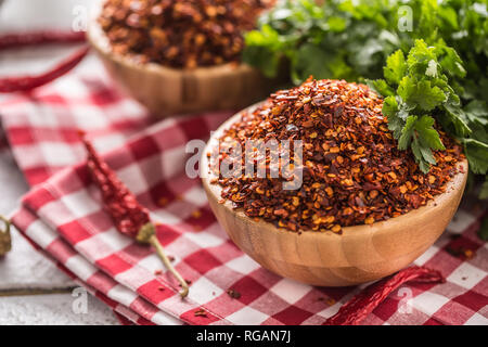 Getrocknet und gemahlen chili peppers in Holz- bowles mit Petersilie Kräuter. Stockfoto