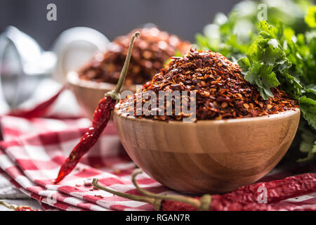 Getrocknet und gemahlen chili peppers in Holz- bowles mit Petersilie Kräuter. Stockfoto