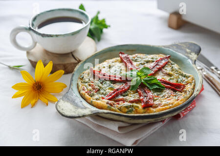 Traditionelle fritatta mit trockenen Tomaten in einer gusseisernen Pfanne. Weißer Hintergrund, Kopie Raum Stockfoto