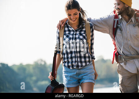 Glückliches junges Paar mit Rucksack und Gitarre im Freien Stockfoto