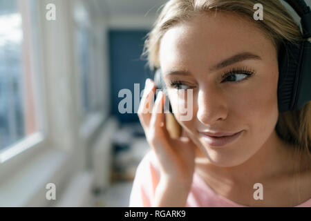 Lächelnde junge Frau hört Musik zu Hause Stockfoto