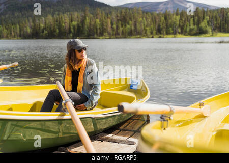 Finnland, Lappland, Frau sitzt in einem Boot auf einem See Stockfoto