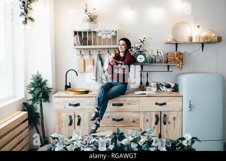 Ein nettes Mädchen sitzt auf einem Tisch in der Küche und isst Kekse mit Schokolade Krümel. Stockfoto