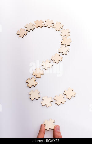 Hand, die das letzte Stück der Fragezeichen. Fragezeichen von Puzzleteile auf weißem Hintergrund Stockfoto