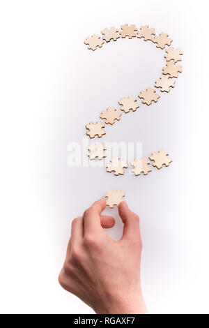 Hand, die das letzte Stück der Fragezeichen. Fragezeichen von Puzzleteile auf weißem Hintergrund Stockfoto