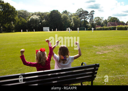Zwei junge Mädchen auf einer Parkbank Cricket beobachten Stockfoto