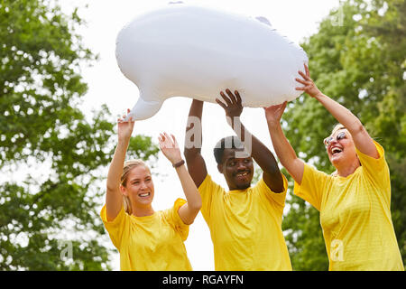 Drei Aktivistinnen im gelben Hemd mit einem weißen Ballon für eine Werbung Stockfoto