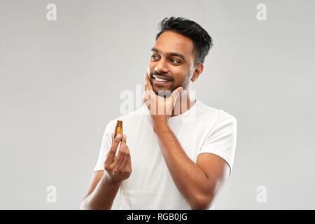 Lächelnd inder Anwendung Pflege Öl zu Bart Stockfoto